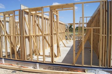 Wooden house frame A mostly-bare wooden house frame occupied with a few scattered drywall sheets